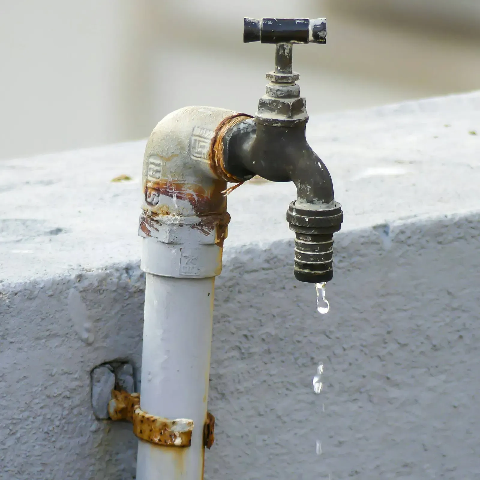 Weathered outdoor tap on a concrete wall